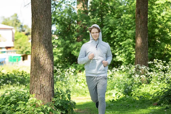 Single young man running in the forest park, street workout. Fitness outside. Exercising alone for Covid-19 revention - Image