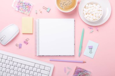Ofis masasında bilgisayar, malzeme, kahve ve pembe arka planda lokum var. Üst Görünüm - Resim
