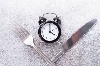 Siyah çalar saat, çatal, arka planda bıçak. Aralıklı oruç kavramı - Resim