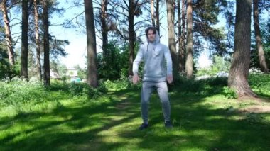 Orman parkında egzersiz yapan bekar bir genç adam, sokak antrenmanı. Fitness dışarıda. Covid-19 'un önlenmesi için tek başına egzersiz yapıyor. 4k görüntü