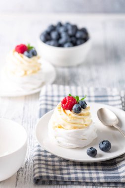 Krem şantili ve beyaz tabakta taze böğürtlenli lezzetli Pavlova pastası.