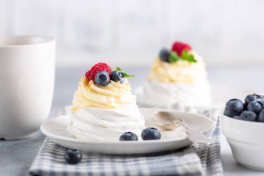 Yeni Zelanda Pavlova pastası, krem şanti ve taze böğürtlen ve kahve kupası.