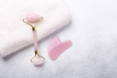 Rose Quartz yeşim taşı silindiri ve Gua Sha masaj aleti taştan arka planda. Yüz bakımı için masaj aracı, SPA güzellik tedavi konsepti - Görüntü