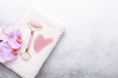 Rose Quartz yeşim taşı silindiri ve Gua Sha masaj aleti taştan arka planda. Yüz bakımı için masaj aracı, SPA güzellik tedavi konsepti - Görüntü