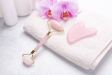 Gua Sha masaj aleti ve arka planda yüz silindiri. Yüz bakımı için masaj aracı, SPA güzellik tedavi konsepti - Görüntü