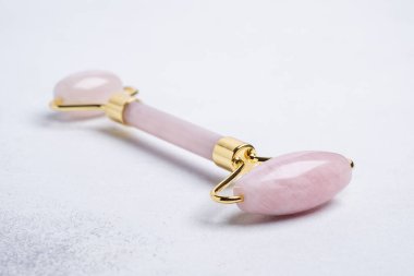 Taş arka planda Rose Quartz yeşim taşı silindiri. Yakın plan. Yüz bakımı için masaj aracı, SPA güzellik tedavi konsepti - Görüntü
