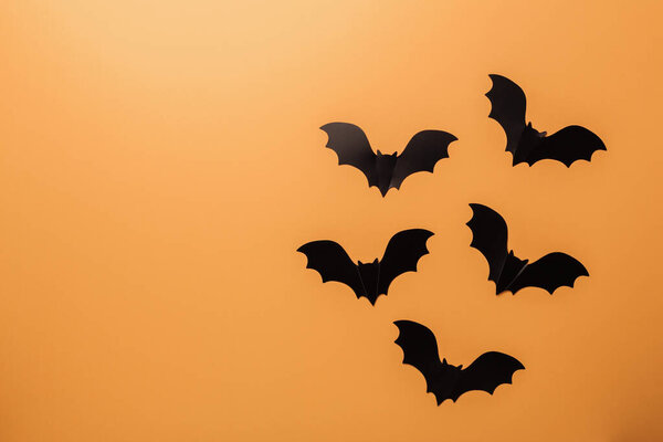 Концепция украшения Хэллоуина. Черные бумажные летучие мыши на оранжевом фоне. Копирование пространства