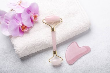 Gua Sha masaj aleti ve arka planda yüz silindiri. Yüz bakımı için masaj aracı, SPA güzellik tedavi konsepti - Görüntü