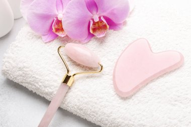 Rose Quartz yeşim taşı silindiri ve Gua Sha masaj aleti taştan arka planda. Yüz bakımı için masaj aracı, SPA güzellik tedavi konsepti - Görüntü