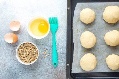 Tavada çiğ hamur parçaları, silikon fırça, yumurta, tohum. Ev yapımı çörekler. Üst Görünüm - Resim