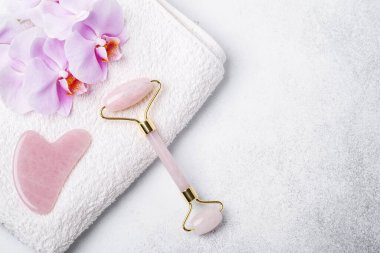 Gua Sha masaj aleti ve arka planda yüz silindiri. Yaş, kaldırma ve tonlama tedavisi. Metnin için alanı kopyala - Resim