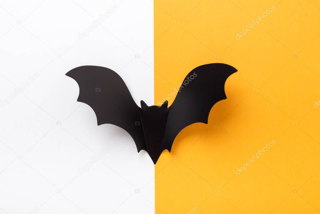 Black paper bat on yellow and white background. Halloween concept. Flat lay, top view, copy space - Image