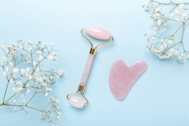 Gua Sha masaj aleti ve yüz silindiri, mavi arka planda Gypthe-ila. Yüz bakımı için masaj aracı, SPA güzellik tedavi konsepti - Görüntü