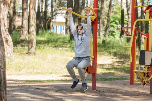 Alleenstaande jongeman doet oefeningen op het sportveld in het park, straattraining. Fitness buiten — Stockfoto