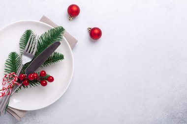 Boş beyaz tabak, şeker kamışı, köknar dalı ve çatal bıçaklı Noel sofrası.