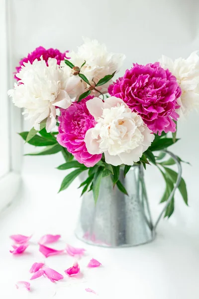 Pencere kenarında bir buket güzel şakayık. Teneke sürahide pembe ve beyaz şakayıklar. Uçan pembe yapraklar. Yumuşak odak - Resim