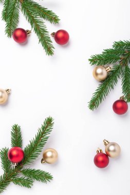 Minimum Noel kompozisyonu. Beyaz arka planda kırmızı ve altın noel topları olan firavun ağacı dalları. Dikey - Resim