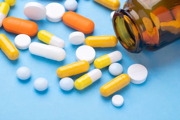 Flerfärgade Tabletter Och Piller Kapslar Från Glasflaska Blå Bakgrund Närbild — Stockfoto