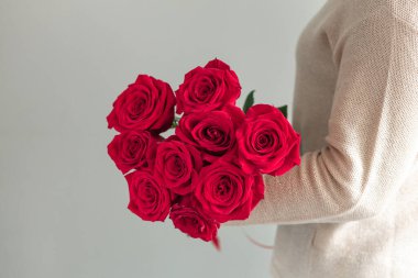 Elinde taze çiçek açan kırmızı güller tutan bir kadın. Uzayı kopyala - Resim