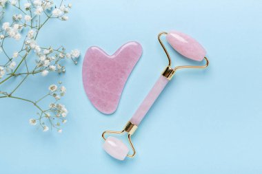 Gua Sha masaj aleti ve yüz silindiri, mavi arka planda Gypthe-ila. Yüz bakımı için masaj aracı, SPA güzellik tedavi konsepti - Görüntü