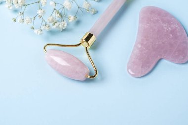 Gua Sha masaj aleti ve yüz silindiri, mavi arka planda Gypthe-ila. Yüz bakımı için masaj aracı, SPA güzellik tedavi konsepti - Görüntü