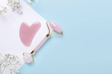 Gua Sha masaj aleti ve yüz silindiri, mavi ve beyaz arka planda gypìila. Yüz bakımı için masaj aracı, SPA güzellik tedavi konsepti - Görüntü