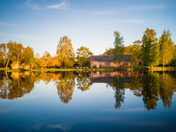 Beautiful Tree Reflection in the Lake on a Sunny Spring Day - Autumn Colours. With a Clear Blue Skies Above them - Symmetric Reflection