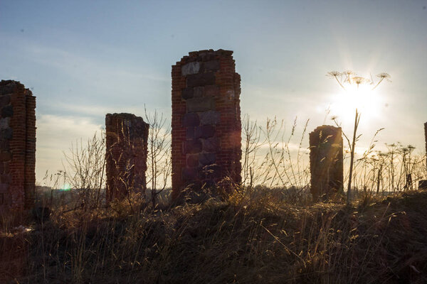 Останки каменной колонны старого здания посреди поля в солнечный весенний день
