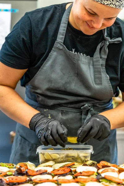 Female Chef Putting Ingredients of Burgers on a Sliced Bread Spread on a Table in Black Gloves - Concept of the Hard Working Person and the Hygiene in the Kitchen