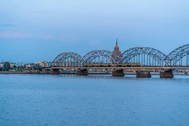 View of Cityscape with Railway Bridge and Train on it in Riga, Latvia, on Blue Hour, Twilight with a Free Space for Text, Concept of Travels in Europe