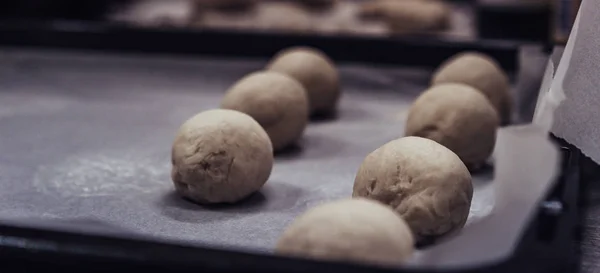 Små bröd degen bollar placeras på matlagning papper på Pan - redo att bakas, Köksset — Stockfoto