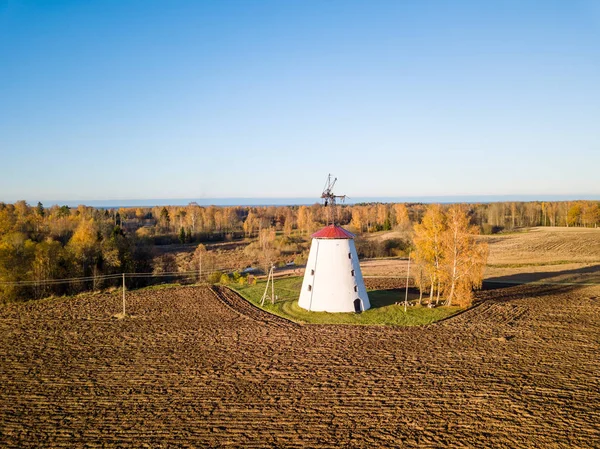 Dron niskiego kąta zdjęcie starego i opuszczonego wiatraka z brzozą pomarańczową obok niego na wsi — Zdjęcie stockowe