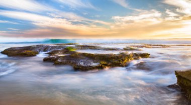 Büyük Otway Milli Park, Victoria, Avustralya Johanna plajda gün batımında üzerinde kayalık tidepools akan okyanus dalgalarının uzun pozlama.
