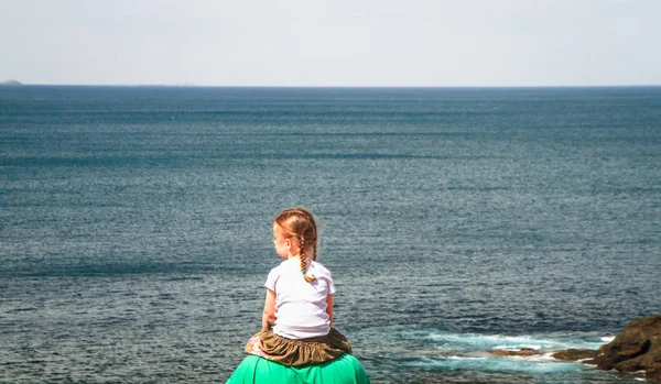 Genç bir kızın babasının omuzlarında oturur ve Cape Schank, Victoria, Avustralya üzerinde okyanus manzarası hayran.