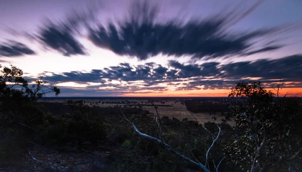 Uzun pozlama sırasında siyah IANS kayalar yakınındaki Grampians Milli Parkı, Avustralya günbatımı manzara karşısında hareket bulutlar.