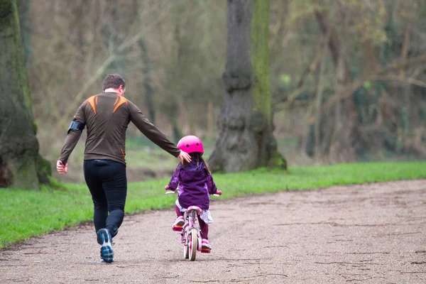 Un padre enseña a su hija a andar en bicicleta Imágenes de stock libres de derechos