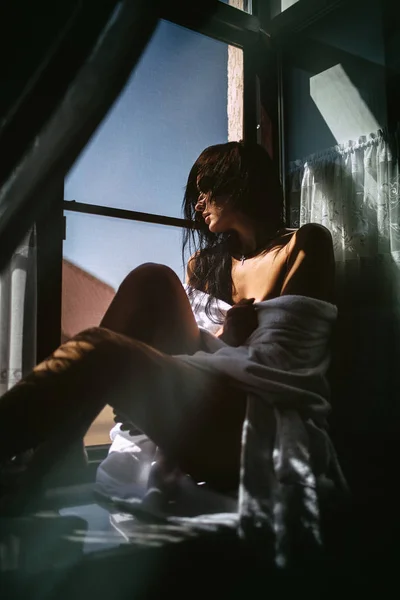 Σέξι κορίτσι σε ένα μπουρνούζι κάθεται στο περβάζι — Φωτογραφία Αρχείου