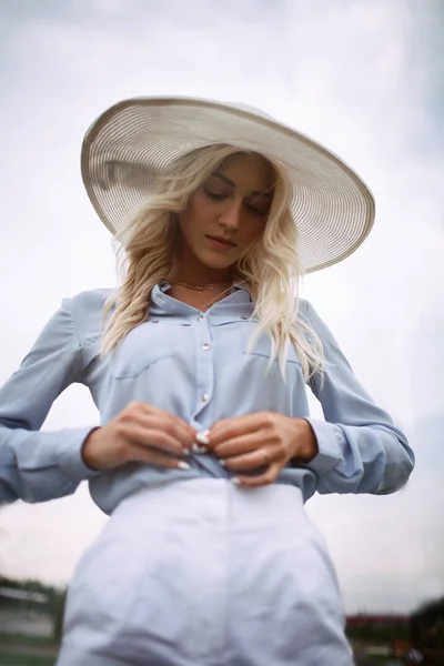 Chica en un sombrero sujeta su camisa — Foto de Stock