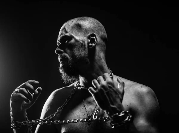 a strong man with a beard in shackles