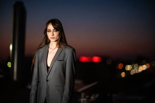 Sexy girl in a voluminous jacket on the background of a night city