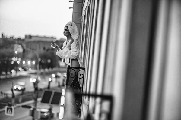 Сексуальная девушка в белом халате стоит на балконе — стоковое фото