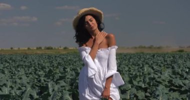 Beyaz elbiseli bir kız yeşil bir tarlada duruyor