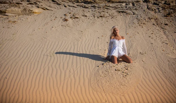 Chica en blanco sentarse en la arena — Foto de Stock