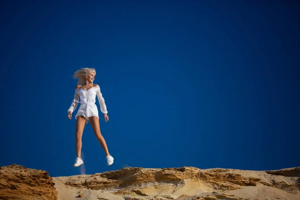 Alegre chica saltando contra el cielo azul — Foto de Stock