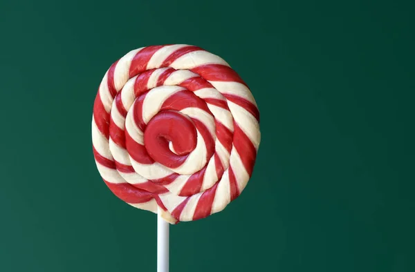 Red lollipop in spiral shape on green background, inspired concept to illustrate Children\'s Day