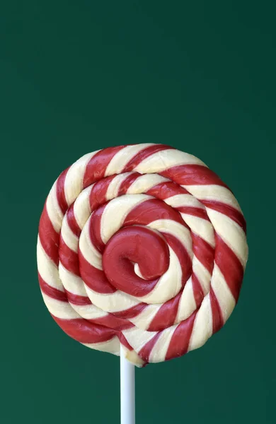Red lollipop in spiral shape on green background, inspired concept to illustrate Children\'s Day