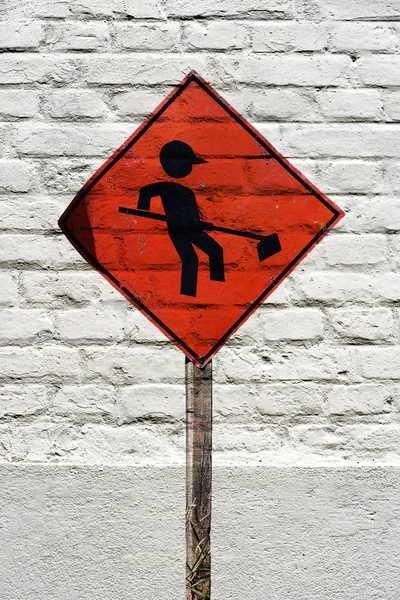 Traffic board signaling workers on the runway stamped on white brick wall, like a graffiti