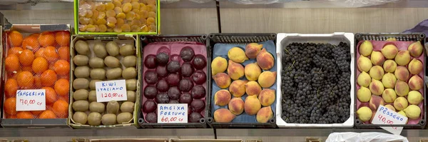 The colorful fruit\'s stalls of the Municipal Market of Sao Paulo, Brazil. Write mandarine, kiwi, plum, and peach in portuguese