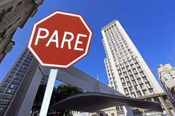City concept: traffic stop plate between buildings in perspective, write stop in Portugues