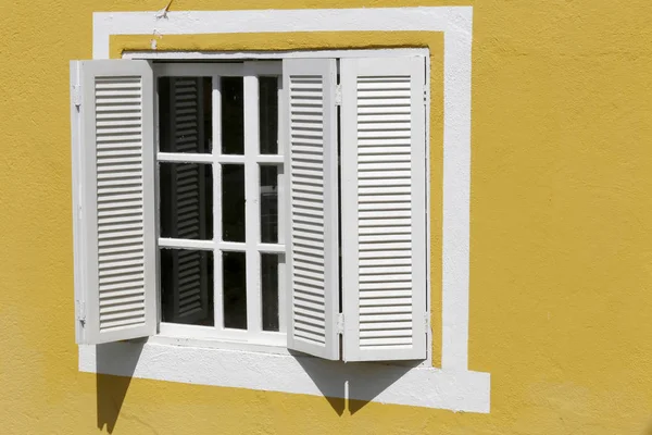 White window on painted yellow wall